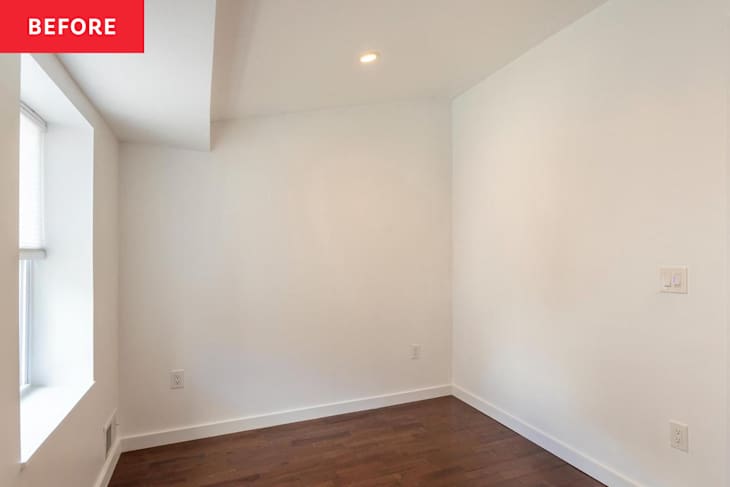 Empty room with hardwood flooring, white walls, a window with blinds, and a light fixture on the ceiling.