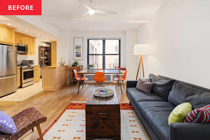 Living room with a gray sofa, wooden coffee table, orange dining chairs, and a kitchen area with light wood cabinets.