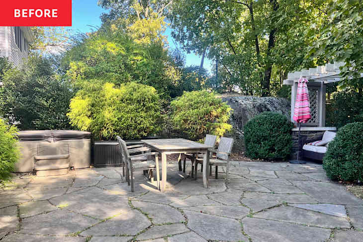 Wooden outdoor dining table on patio with stone pavers.