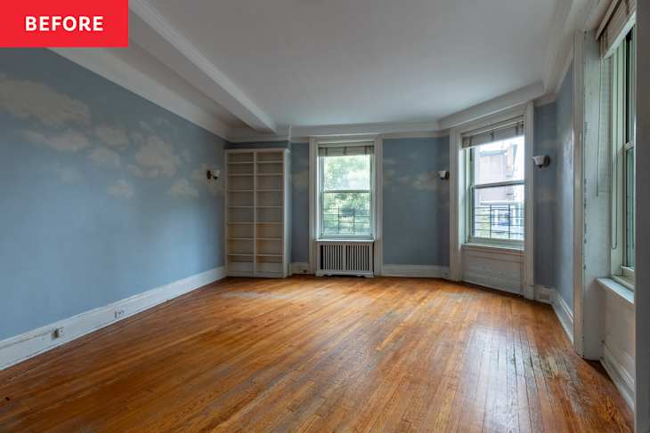 Empty room with light blue walls featuring cloud patterns, hardwood floor, and a white bookshelf.