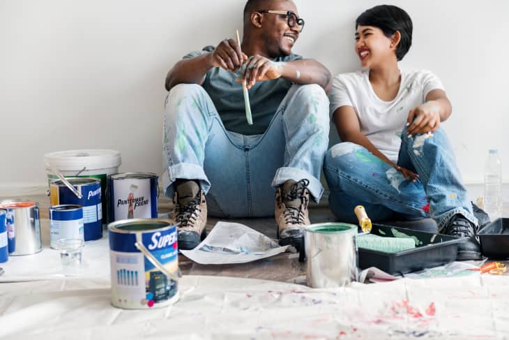 Couple painting house wall