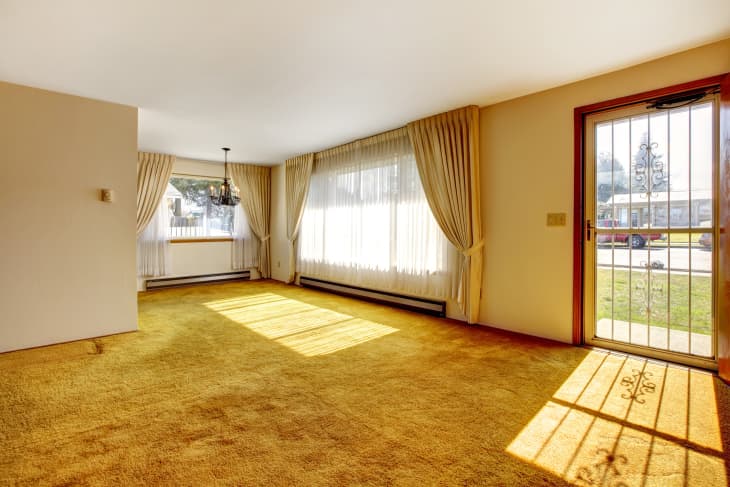 Empty bright room with one window, beige carpet floor