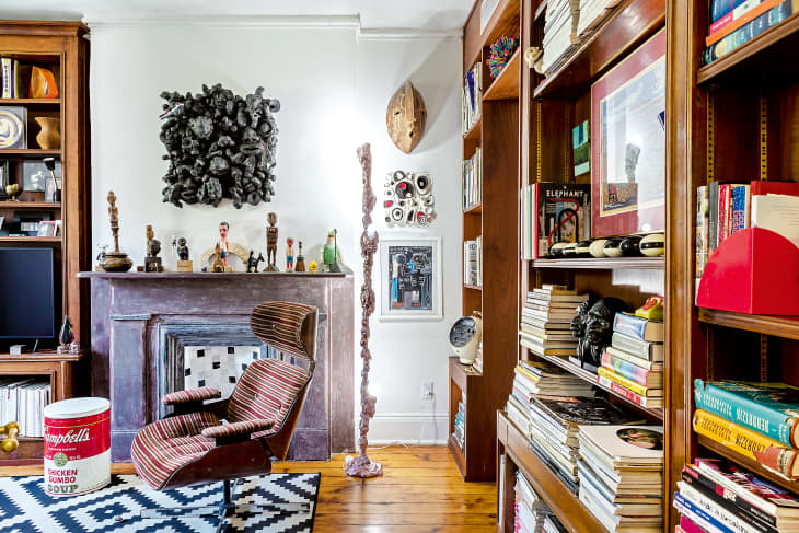 A living room with a chair in front of a fireplace and a large built-in bookcase