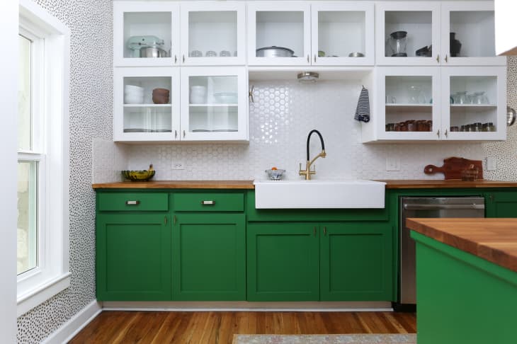 Kitchen with green lower cabinets, white upper cabinets, hexagonal tile backsplash, and a farmhouse sink.