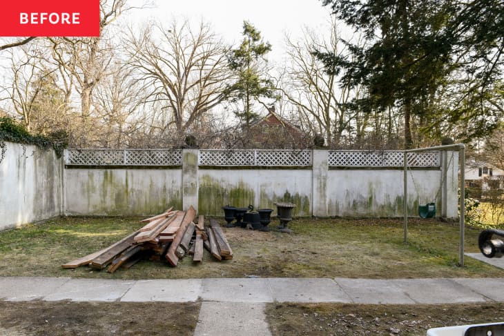 Piles of wood planks in backyard with moss and algae growing on side wall before renovation.