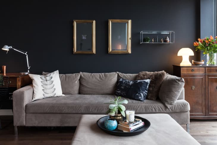 a living room with a black wall and gray sofa