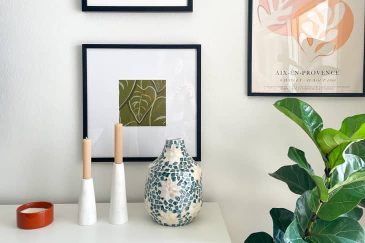 corner of room with book shelf, candle sticks, and art on wall, flower vase