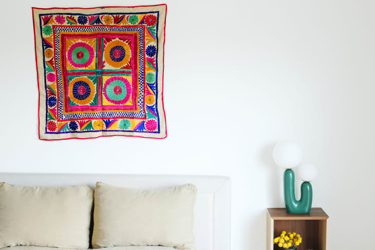 Colorful tapestry hung above bed.