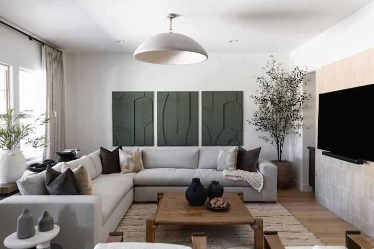 Cozy living room with a sectional sofa, decorative pillows, a wooden coffee table, and green wall art.
