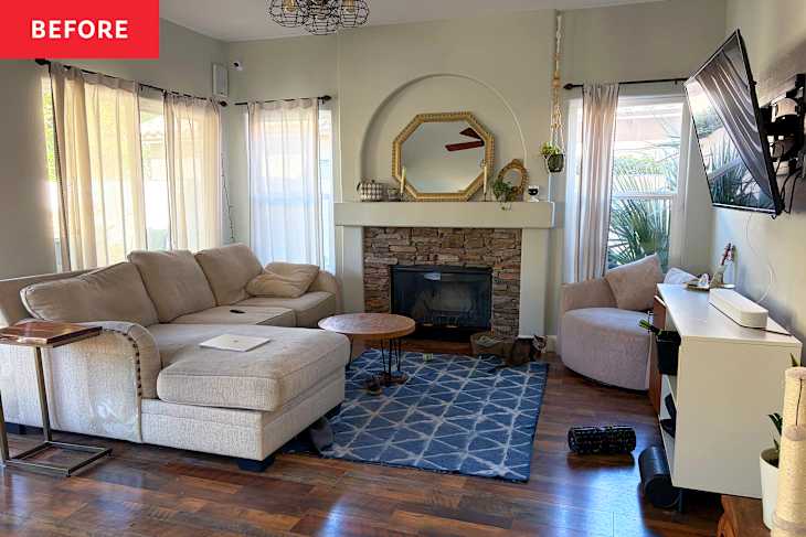 Living room with a beige sectional sofa, stone fireplace, round coffee table, and a TV mounted on the wall.