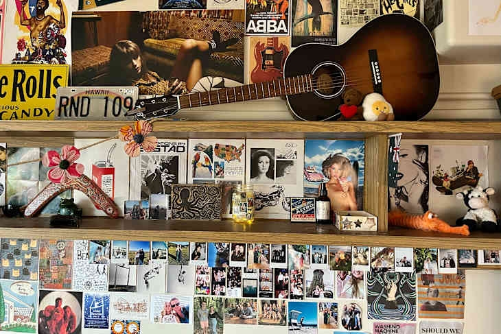 Guitar on shelf in dorm room with photo collage.