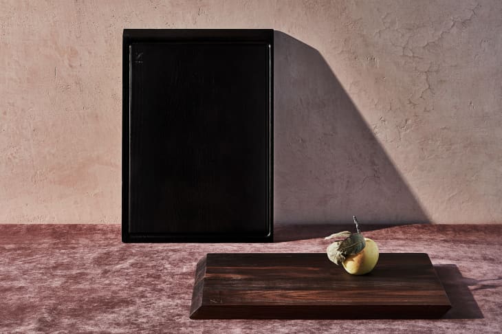 Two dark wooden cutting boards on a textured surface, one with a quince.