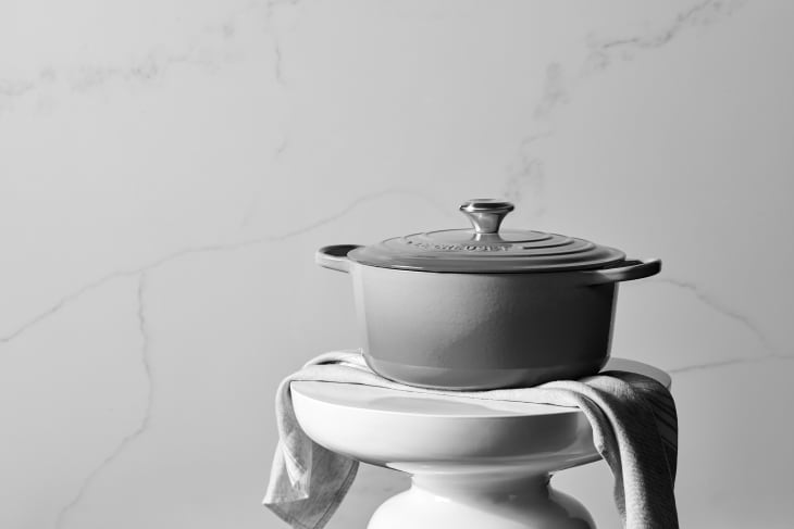 Gray cast iron Dutch oven on a pedestal with a draped cloth.