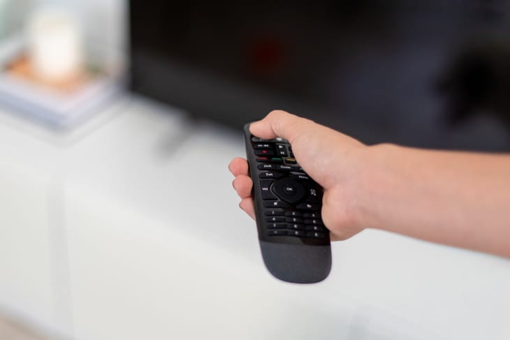 A person using a remote to turn off a televsion