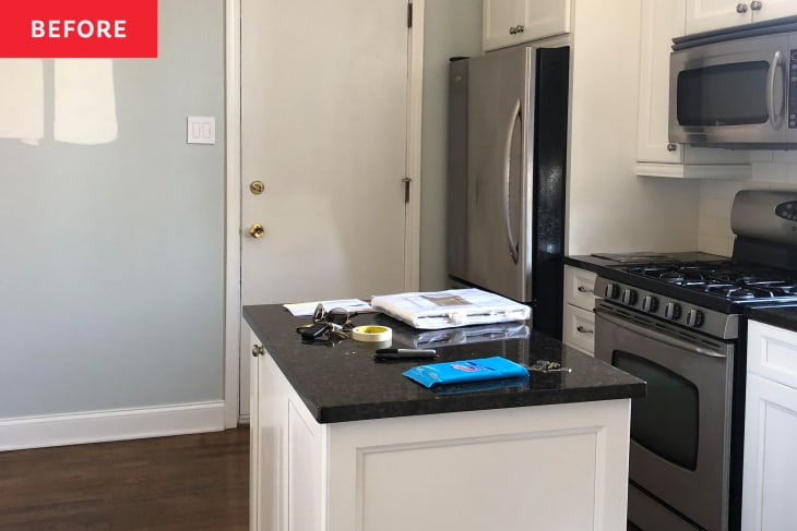 Kitchen with white island, cabinetry. and black countertops.
