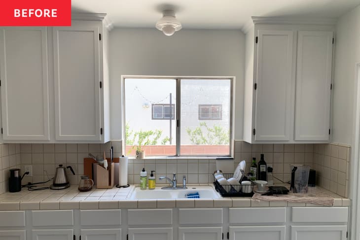 Kitchen with white cabinetry and light tile before renovation.