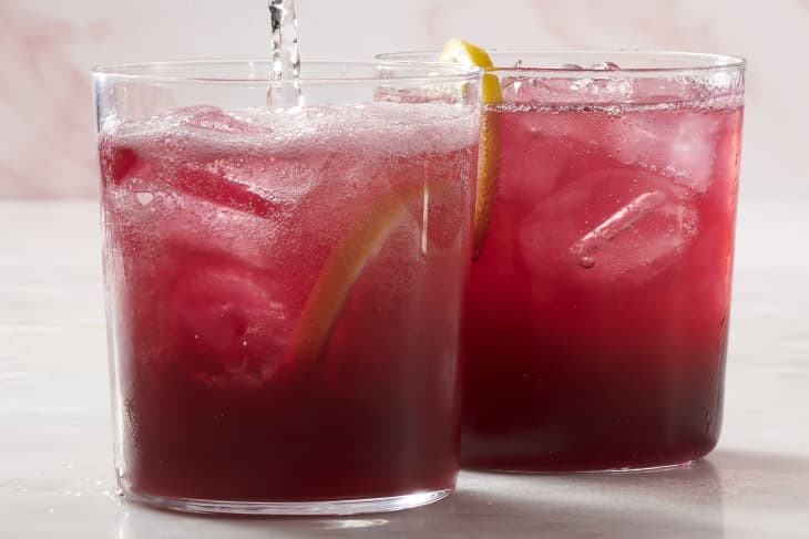 A photo of 2 glasses of red tinto de verano cocktails. The glass in the front is getting seltzer poured in.