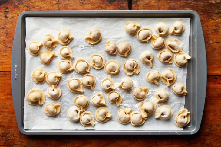 Pelmeni's are folded and on a sheet pan lined with parchment.