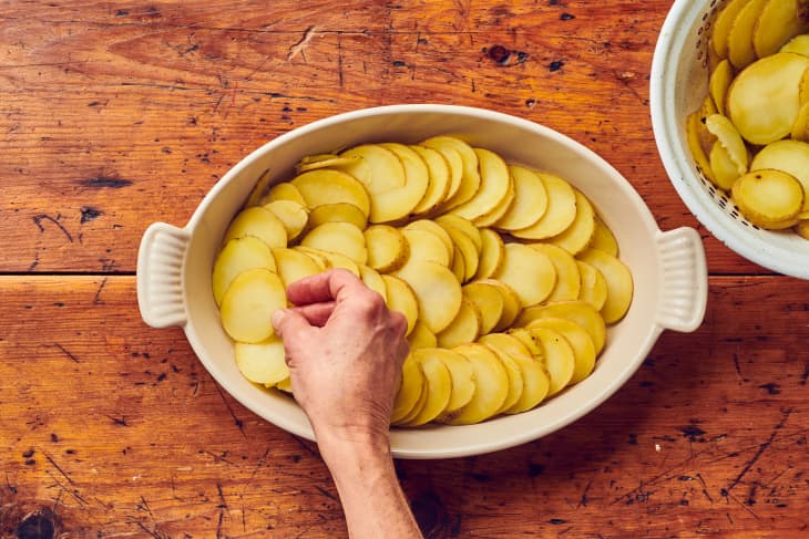 someone is placing cut circular potatoes om large circular plate