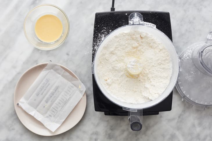 four sits in a food processor next to a package of butter