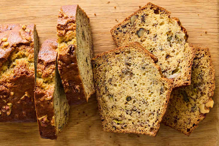 banana bread on brown cutting board with slices falling off