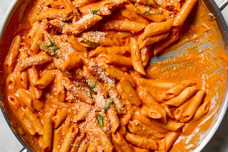 overhead shot of penne alla vodka in a pan, topped with parmesan and basil