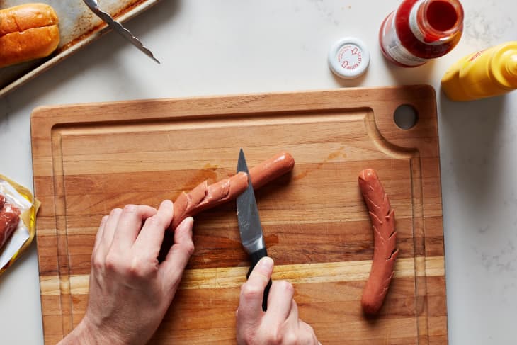 Someone slicing hot dog using fish scale method.