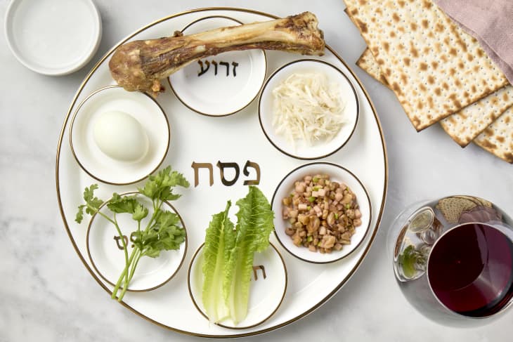 overhead shot of a full sedar plate with matzo and a glass of red wine on the side.