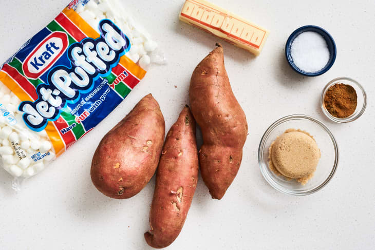 Sweet potatoes, marshmallows, butter, brown sugar, cinnamon, and salt arranged on a countertop.