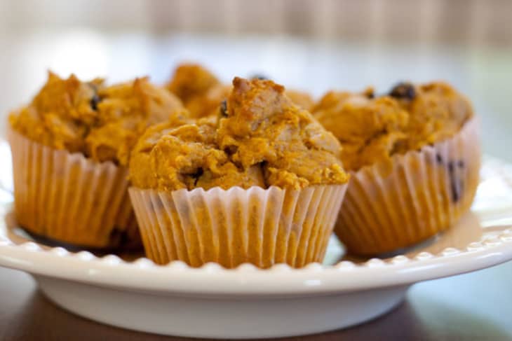 Pumpkin muffins with chocolate chips on a white plate.