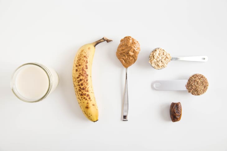 a banana and spoons with a glass of milk, the ingredients of the banana bread protein shake