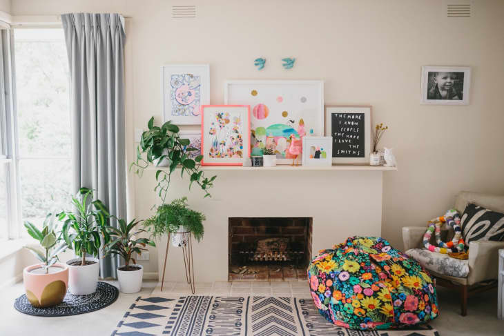 Living room with colorful bean bag, potted plants, framed art, and a letter board on the mantel.