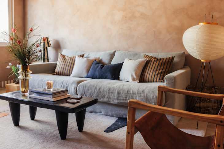 Cozy living room featuring a light gray sofa with striped and solid pillows, a black coffee table, and a decorative floor lamp.