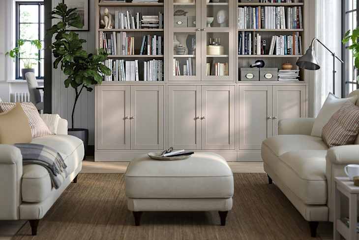 Cozy living room with light-colored sofas, a coffee table, and a tall bookshelf filled with books and decor.