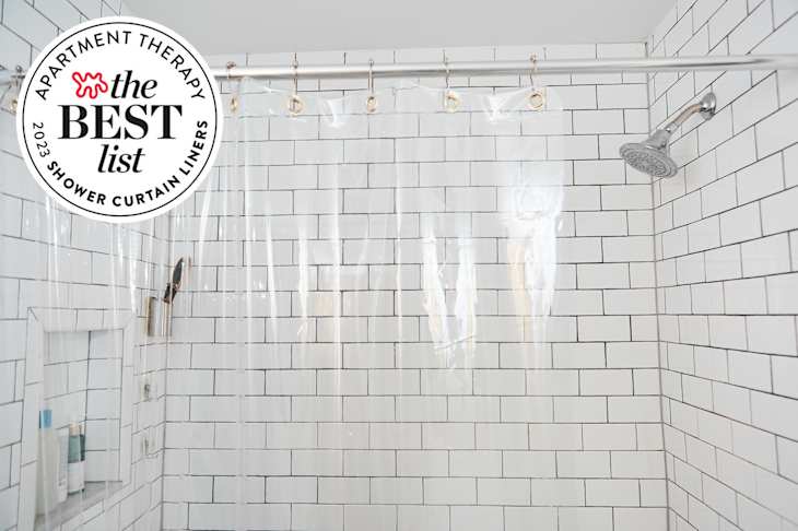 White tile and black grout shower with clear curtain liner. Seal in upper left corner reads "Apartment Therapy The Best List: 2023 Shower Curtain Liners"