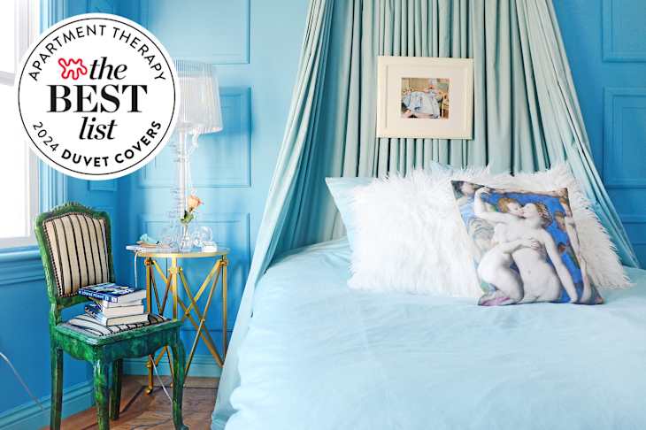 Bright blue bedroom featuring a bed with a fluffy white pillow, a green striped chair, and a glass lamp.