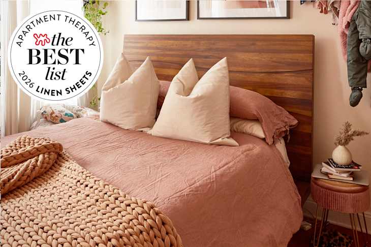 Cozy bedroom featuring a wooden headboard, pink linen bedding, large pillows, and a braided throw blanket.