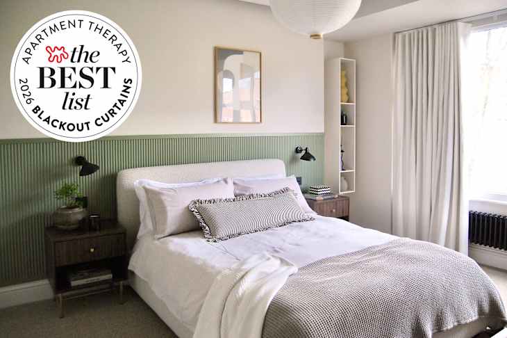Cozy bedroom featuring a green accent wall, a bed with layered bedding, a nightstand, and a window with white curtains.