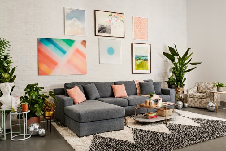 Small Cool 2022 Experience lounge space with gray sofa, small gallery wall, plants, black and ivory geometric rug, checkered accent chair, disco balls on floor