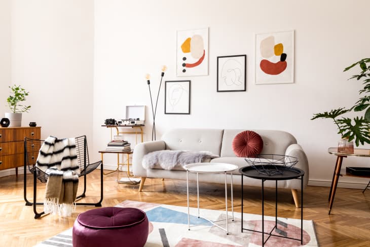 living room decorated with grey sofa, armchair, retro commode and posters on the wall