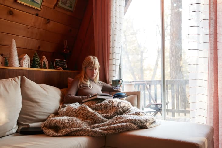 Woman reading book on sofa at home