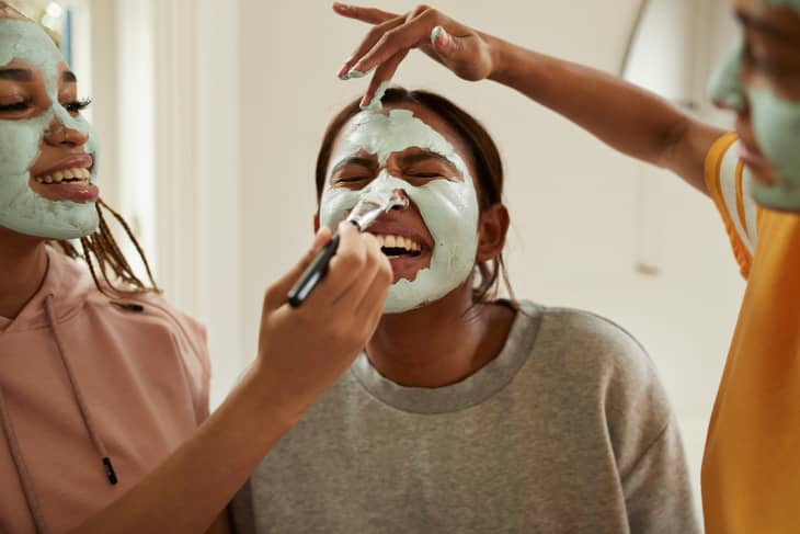 Young woman enjoying friend's applying cream on face
