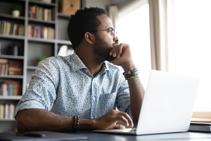 Thoughtful serious man sit with laptop thinking of project.