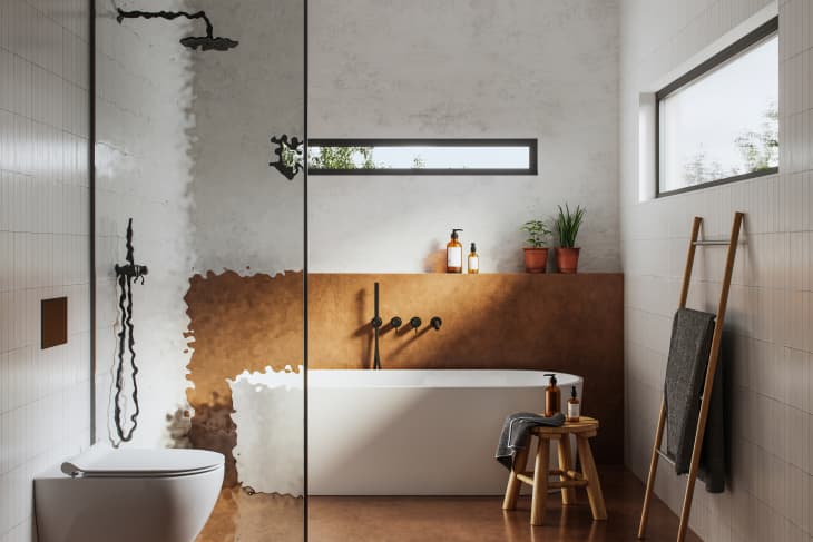 wet room style bathroom with freestanding tub, shower, brown floors, white tile walls