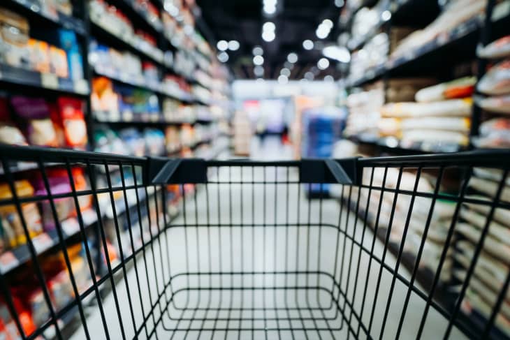 Personal perspective of a shopper pushing shopping trolley along product aisle while shopping in a supermarket