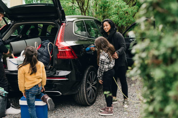 Family packing up car to go on road trip, camping