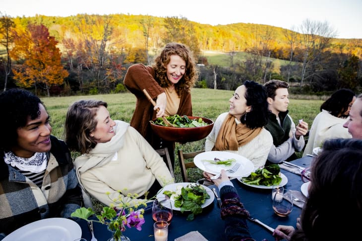 Woman serving salad to friends at dinner party
