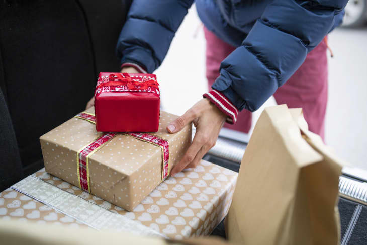 Man putting wrapped gifts in the trunk of a car