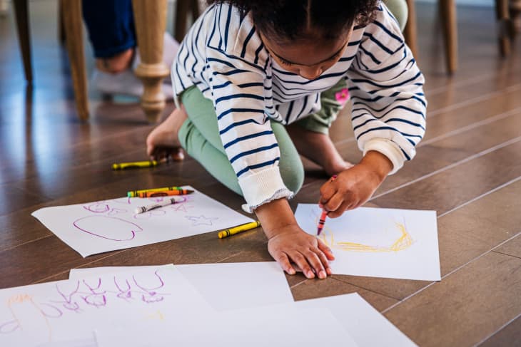 Girl drawing with crayons on paper at home