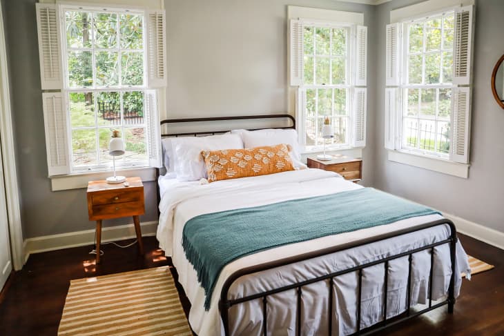 A guest bedroom with a queen sized bed and nightstand at a short term rental small cottage style house.